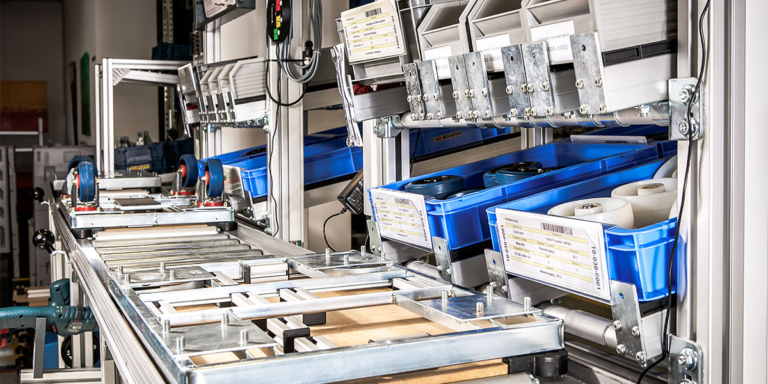 Montagearbeitsplatz mit E-Kanban-System, das Material nachschiebt, um Lagerbestände niedrig zu halten und die Produktion kontinuierlich zu versorgen - Beitragsbild