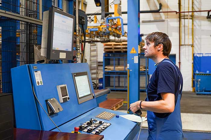 Mitarbeiter steht an einer Maschine und erfasst Betriebsdaten digital - für eine schnelle, einfache und fehlerfreie Datenerfassung