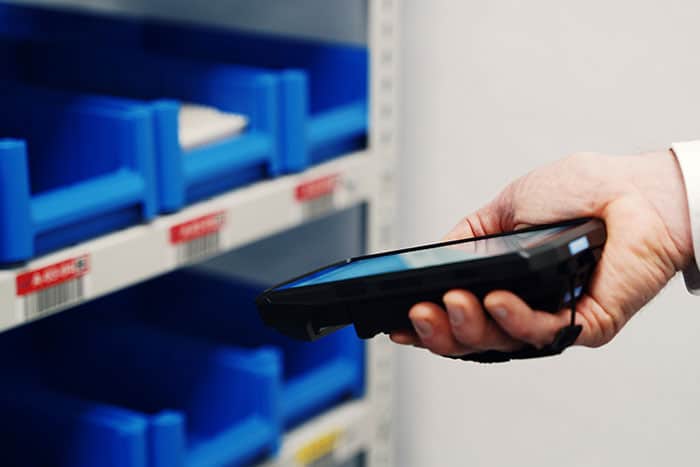Mitarbeiter erfasst den Materialbestand mit einem mobilen Endgerät und löst bei Bedarf automatisch eine Nachschubmeldung im Kanban-System aus