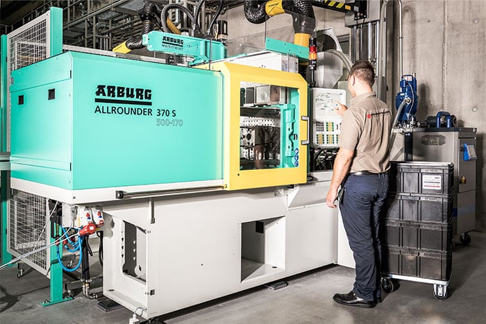 Ein Mitarbeiter steht vor einer Maschine, die an die automatisierte Maschinendatenerfassung angebunden ist,