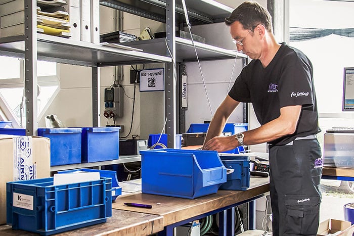 Mitarbeiter füllt eine KLT-Box mit Material im Lager auf – Lagerbestände mit E-Kanban effizient verwalten und Nachschubprozesse optimieren.