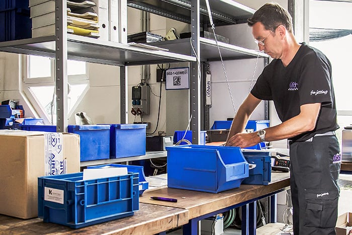 Ein Mitarbeiter befüllt Materialboxen im Pufferlager – ein Beispiel für die manuelle Steuerung von Pufferbeständen mit einem klassischen Kanban-System