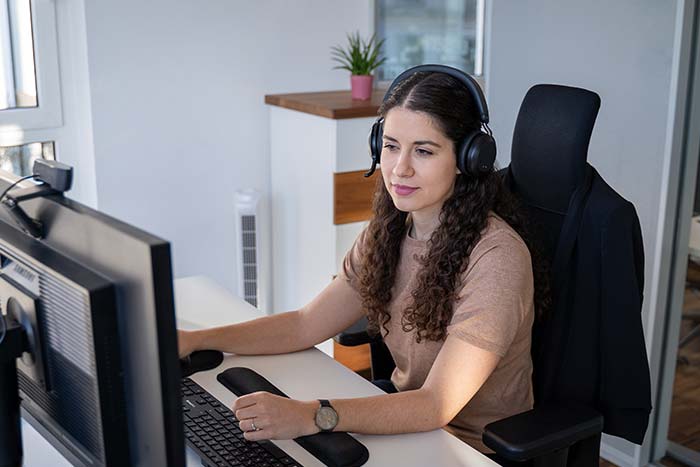 servicemitarbeiterin-im-innendienst-am-telefon Servicemitarbeiterin im Innendienst mit Headset telefoniert mit dem Kunden und arbeitet parallel mit einer FSM-Software