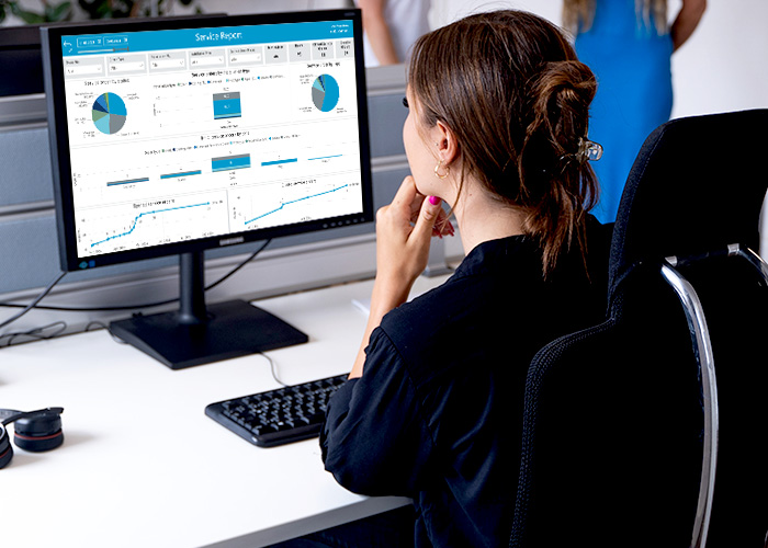Transparenz und Steuerung im Field Service durch FSM Software Innendienstmitarbeiterin schaut Servicereporting an